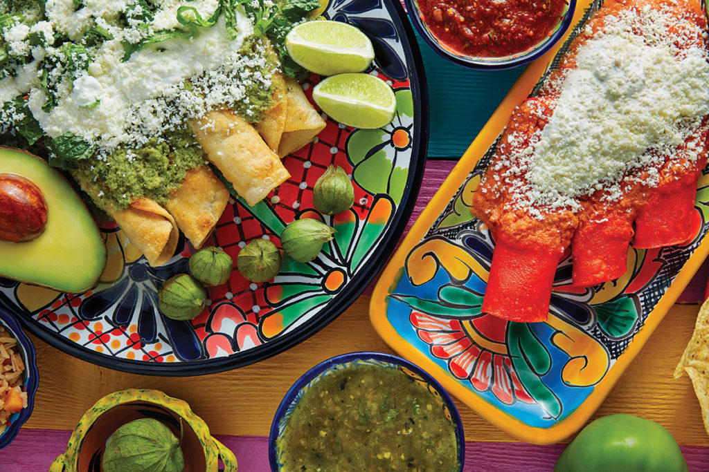 Green and red enchiladas with mexican sauces mix in colorful table