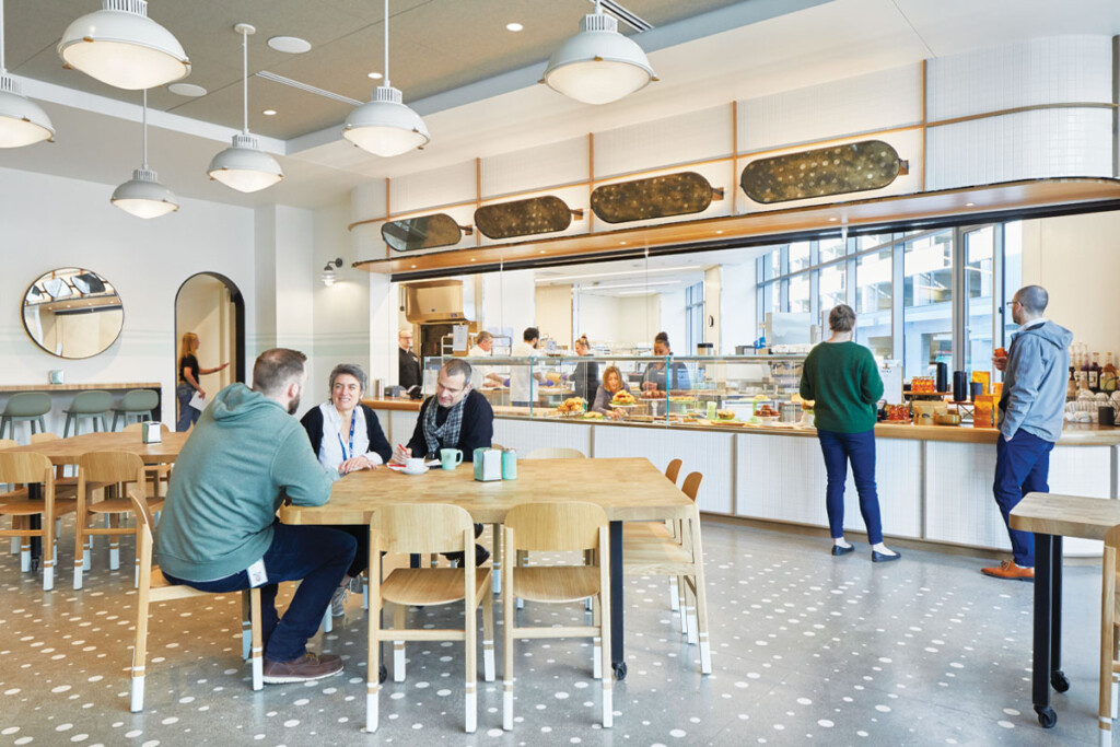 A bakery/cafe anchors Expedia Group’s corporate dining facility. A full wall of windows offers a view of baking action to people walking along the sidewalk toward the main entrance.