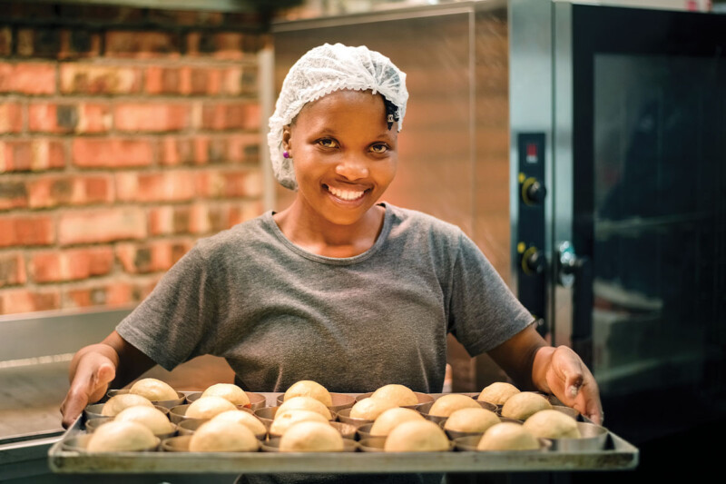 Kitchen staff holding tray of dough