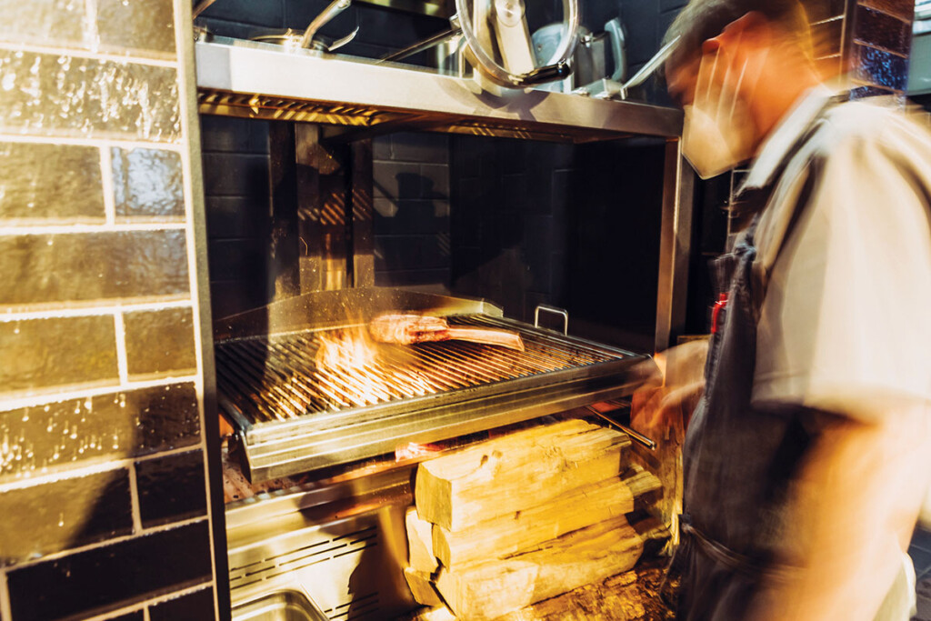 A wood-fired charbroiler serves as the heart of the tavern’s cookline. Its control wheel and counterweights allow cooks to raise and lower the grill as needed.