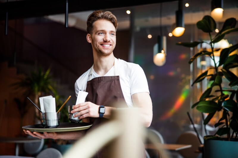 Young waiter working in cafe