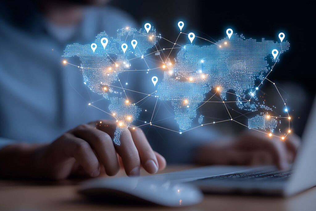 Global Connection: A person is working on a laptop with a holographic projection of the world map and location pins, illustrating the concept of global network, technology, and worldwide reach.
